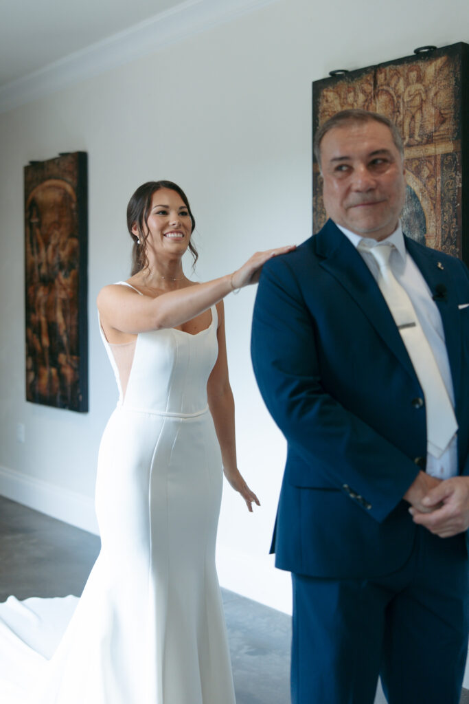 Bride tapping her father on the shoulder before their first look.