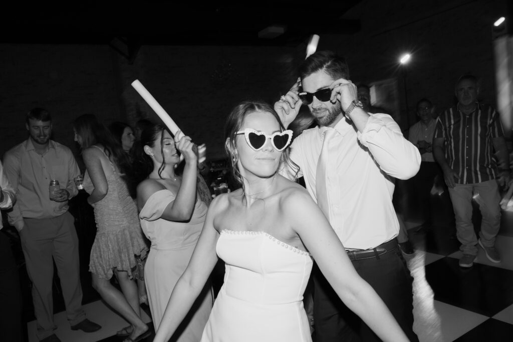 Wedding photography on film of the bride and groom dancing while wearing fun glasses.