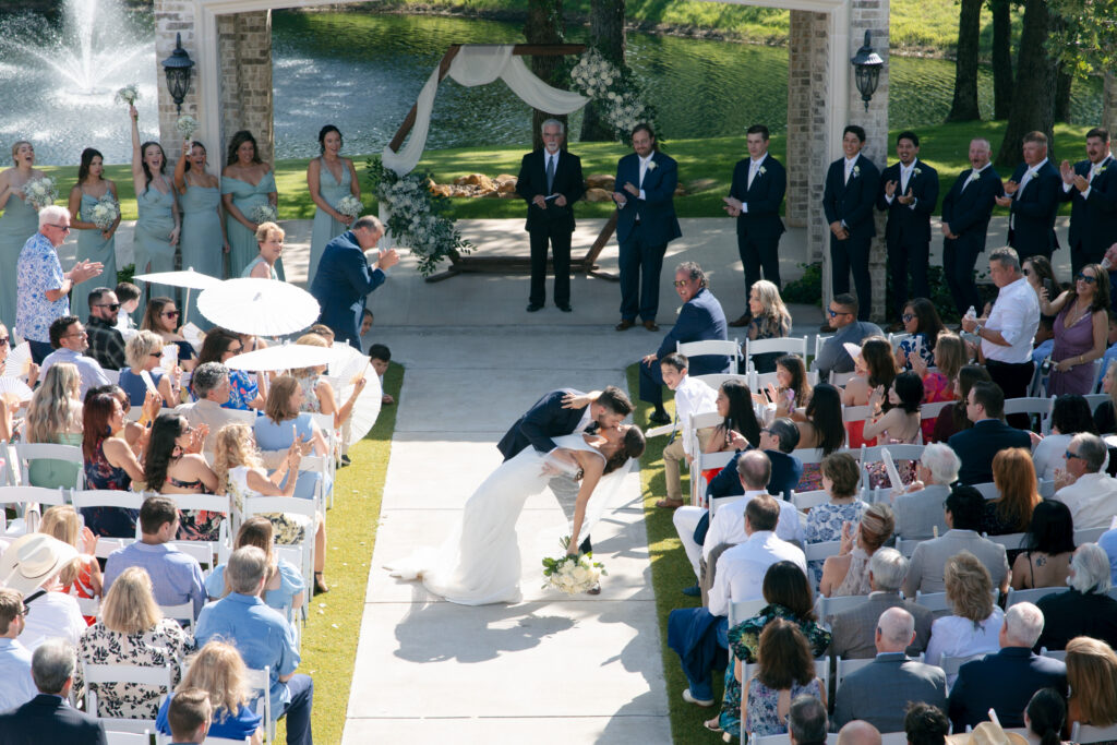 Bride and groom kissing in the middle of the ceremony aisle. 