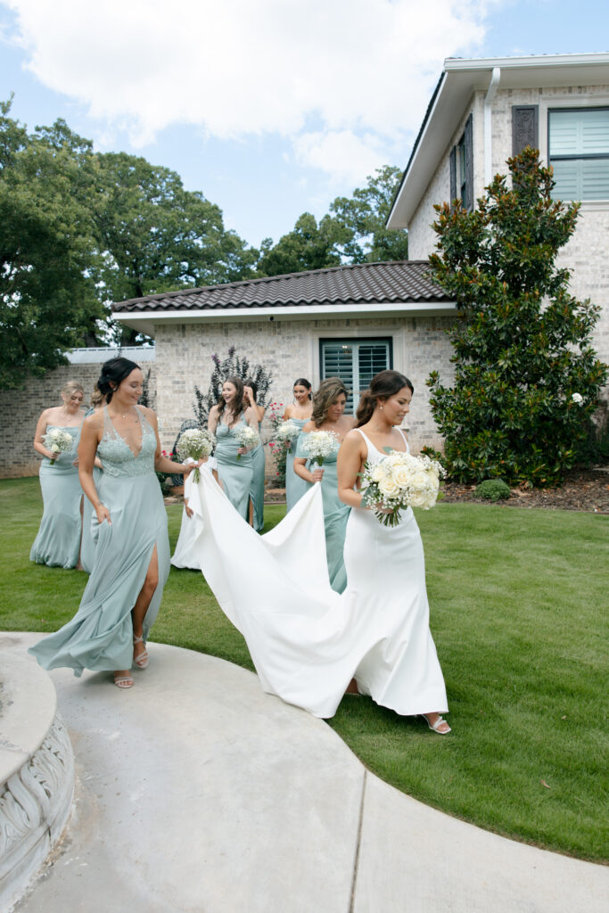Wedding photography on film of the bridal party walking while holding the bride's train.