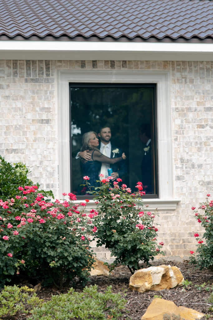Groom and his mother looking out a window before the ceremony.