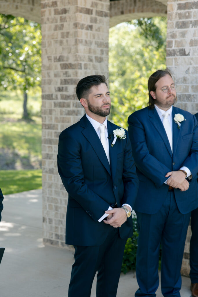 Groom standing during the ceremony, looking at the bride.