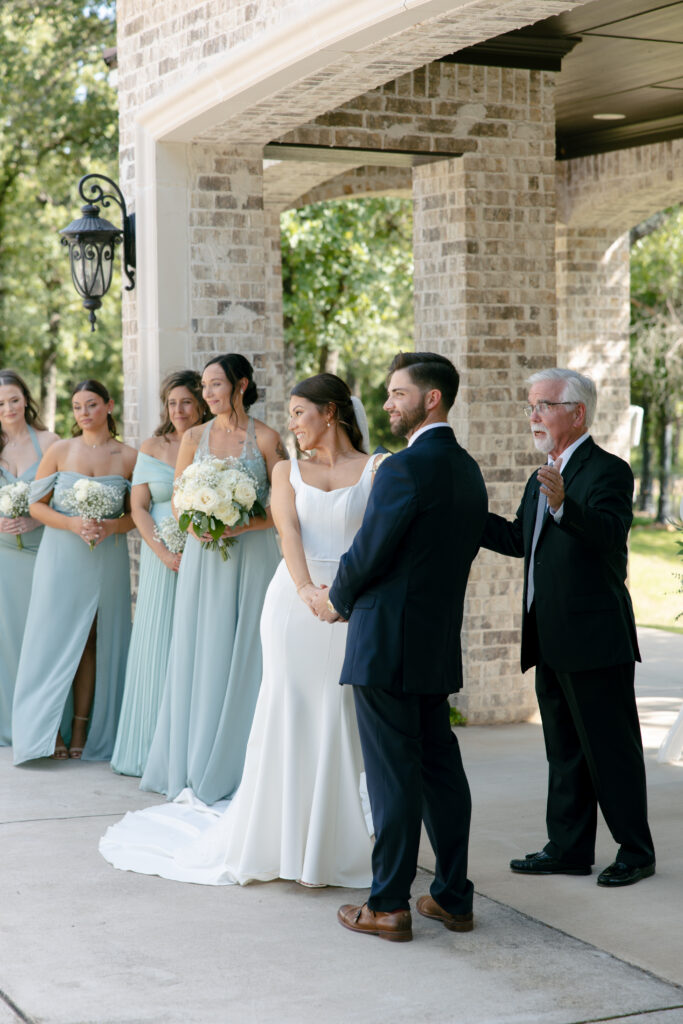 Bride and groom holding hands looking at the wedding guests.