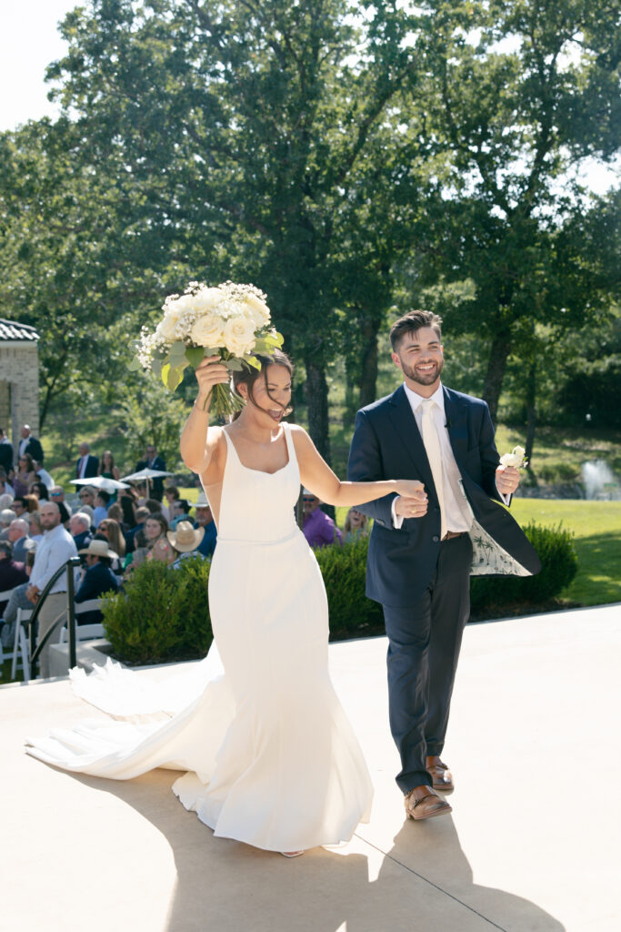 Bride and groom cheering as they leave the ceremony.