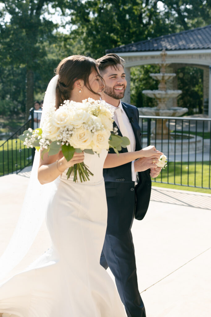 Bride and groom holding hands, walking away from the ceremony.