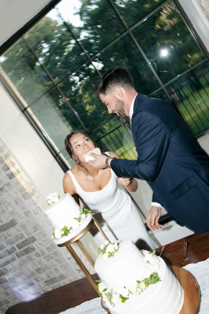 Wedding photography on film of the groom feeding the bride a big slice of cake.