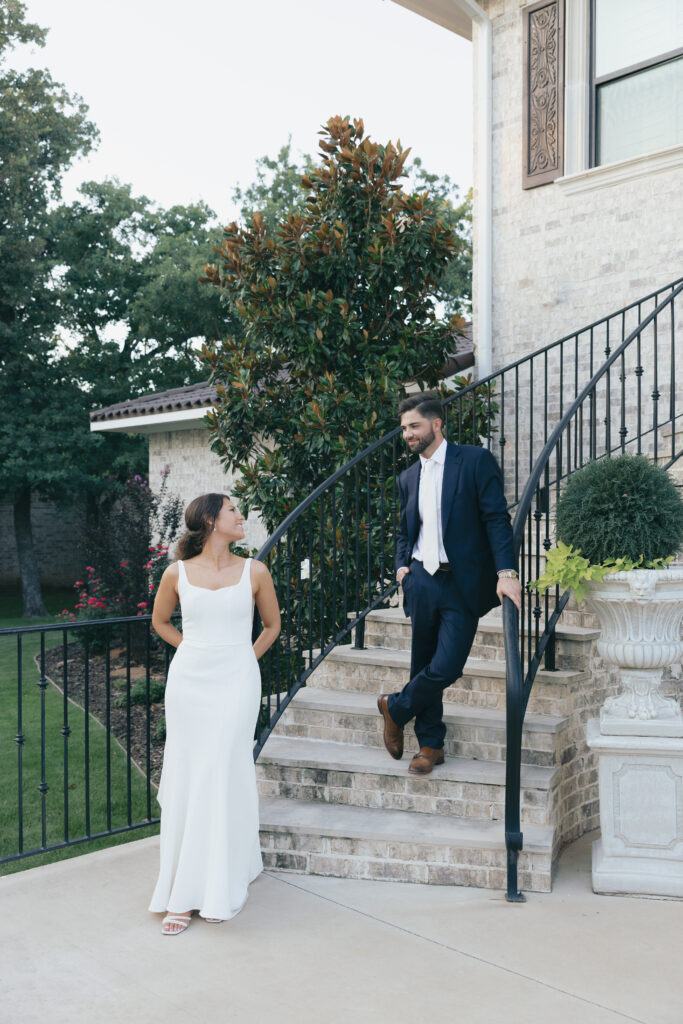Wedding photography on film of the groom standing on the steps looking down at his bride.
