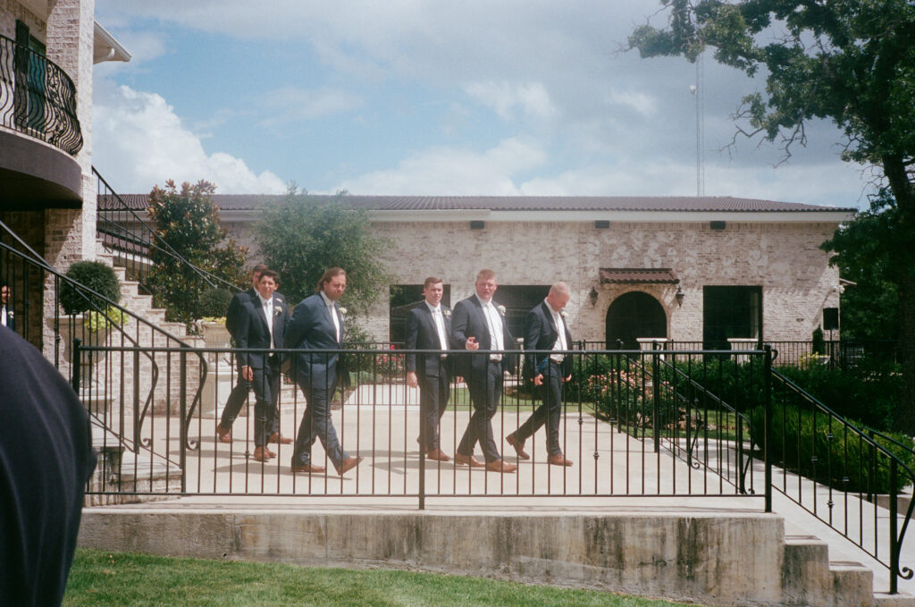 Wedding photography on film of groomsmen walking outside of La Bella Luna.