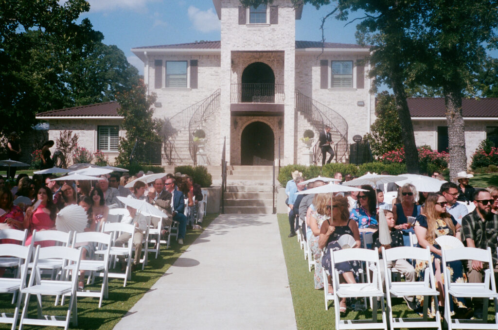 Wedding photography on film of wedding guests sitting during the wedding ceremony at La Bella Luna in Granbury, Texas.
