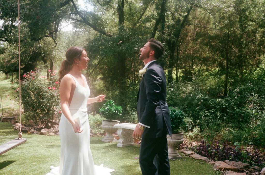 Wedding photography on film of bride and groom laughing together during their first look.
