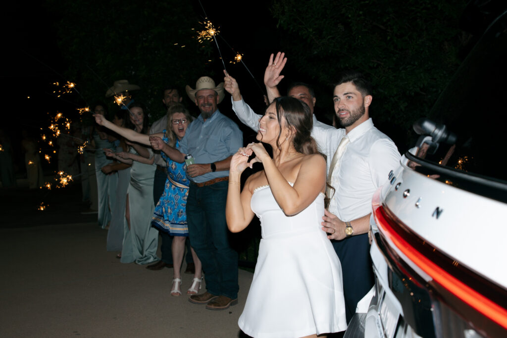 Bride and groom waving goodbye to the wedding guests during the sparkler exit.