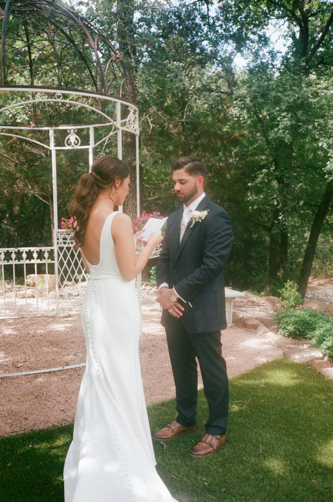 Wedding photography on film of a bride reading personal vows to her soon to be husband during their first look.