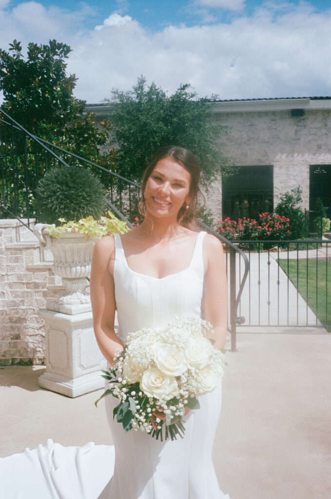 Wedding photography on film of a bride smiling, holding her wedding bouquet.