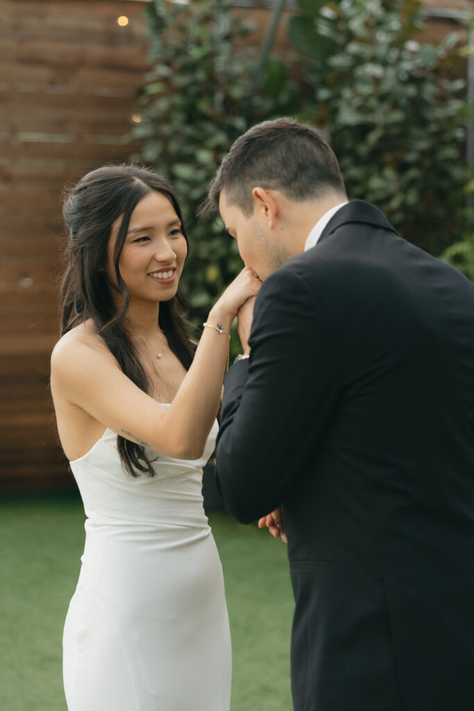Groom kissing his bride's hand.