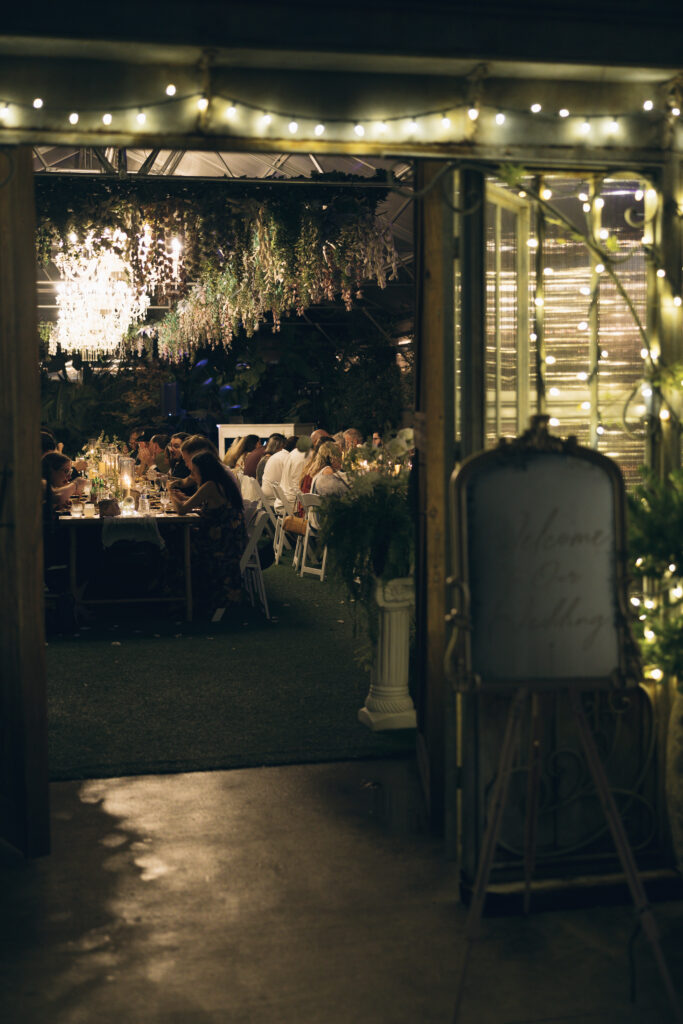 Wedding reception dinner with string lights and greenery.