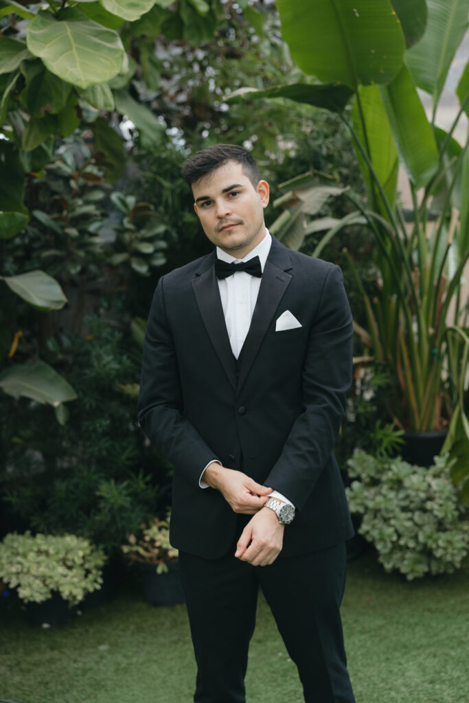 Groom posing with lush greenery behind him at Honey Locust Farms in Rockwall, Texas.