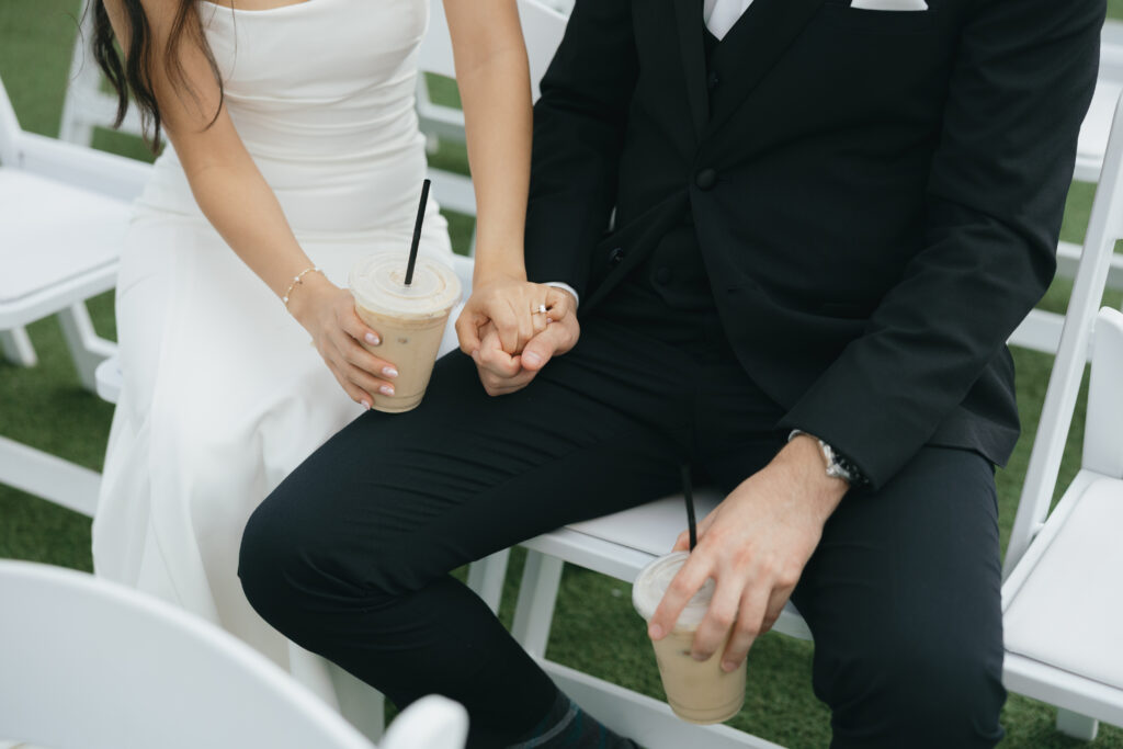 Bride and groom holding hands with one hand and holding coffee in the other before the ceremony at Honey Locust Farms in Rockwall, Texas.