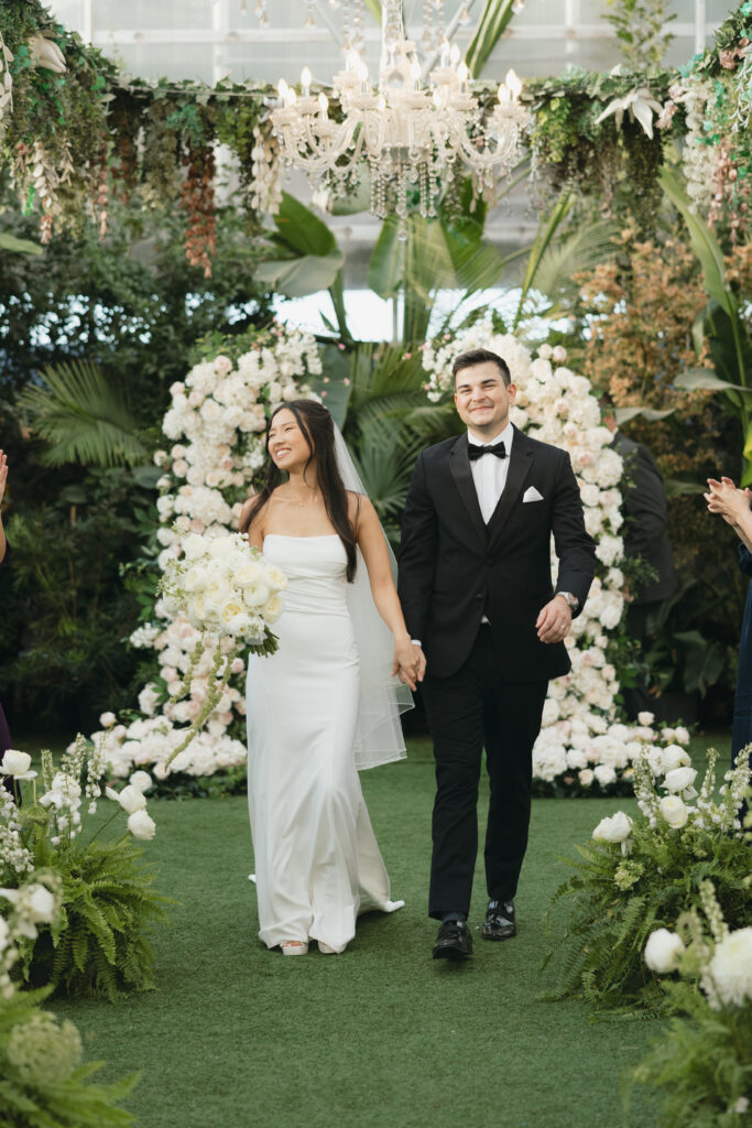 Bride and groom walking down the aisle while smiling at guests. 