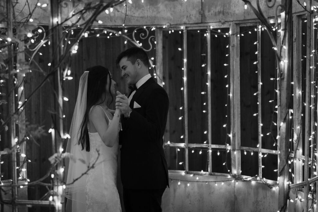 Bride and groom slow dancing under string lights, one of their intimate wedding ideas.