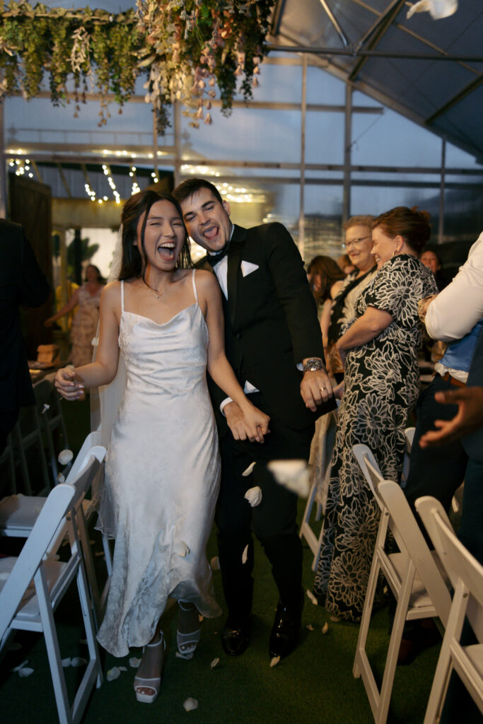 Couple walking through guests cheering.