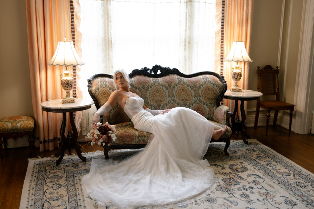 Woman sitting on a vintage couch at the Aldredge House for bridal portraits. 