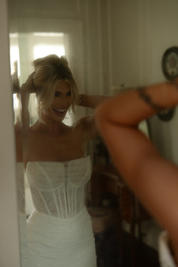 Bridal playfully touching her hair in the mirror.