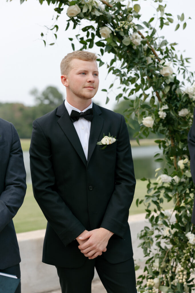 groom holds back tears as his bride comes down the aisle at the outdoor wedding ceremony at Margot Hill
