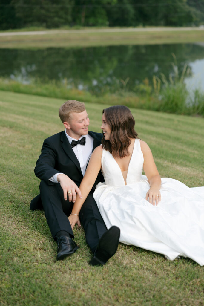 bride and groom looking at each other and smiling by the water